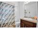 Well-lit bathroom features a shower-tub combo with colorful curtain and a vanity with a dark-wood cabinet at 2129 Stillwood Way, St Cloud, FL 34771