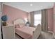 Charming pink bedroom with a classic white bed, complemented by a globe and soft, natural light at 2129 Stillwood Way, St Cloud, FL 34771