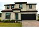 Charming two-story home featuring a brick driveway, neutral stucco, dark trim, and a teal front door at 220 Brookes Pl, Haines City, FL 33844
