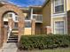 Charming yellow condo building with brick features, private balconies, and lush green landscaping at 2494 Sweetwater Club Cir # 55, Kissimmee, FL 34746