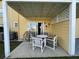 Covered patio area with table and four chairs near sliding glass doors on a sunny day at 2494 Sweetwater Club Cir # 55, Kissimmee, FL 34746