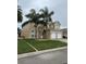 Stucco two-story home featuring a two-car garage, well-kept lawn, and tropical landscaping at 2663 Sand Hill Point Cir, Davenport, FL 33837
