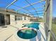 Outdoor pool with a screened enclosure, complemented by a relaxing spa at 296 Sand Ridge Dr, Davenport, FL 33896