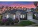 Charming single-story home boasts lush landscaping, arched windows, and attached two-car garage at sunset at 311 N Hampton Dr, Davenport, FL 33897