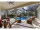 Relax with a large pool, outdoor furniture, screened enclosure, and mature landscaping at 311 N Hampton Dr, Davenport, FL 33897