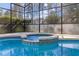Relax in this in-ground spa with mosaic tile and screened enclosure surrounded by mature landscaping at 311 N Hampton Dr, Davenport, FL 33897