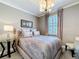 Comfortable bedroom with stylish decor, including a plush bed, a decorative lamp, and natural light from the window at 3240 Songbird Cir, Harmony, FL 34773