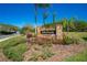 Stone sign at the entrance of 'Sawgrass' community, landscaped with lush greenery and palm trees at 3303 Ann Arbor Ct, St Cloud, FL 34772