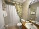 Cozy bathroom with a shower/tub combo, neutral tile, and a charming leaf-patterned shower curtain at 4602 Cumbrian Lakes Dr, Kissimmee, FL 34746