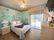 Whimsical bedroom with unique mural, white furniture and an outdoor view through sliding glass doors at 4602 Cumbrian Lakes Dr, Kissimmee, FL 34746