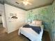 Charming bedroom with colorful mural, light wood floors and a comfortable bed with a gray blanket at 4602 Cumbrian Lakes Dr, Kissimmee, FL 34746