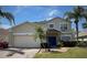Inviting home exterior showcasing a two-car garage, palm trees, and a stone-accented entrance at 4602 Cumbrian Lakes Dr, Kissimmee, FL 34746