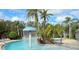 A view of the community pool with tropical landscaping, featuring a unique mushroom-shaped water feature, under a partly cloudy sky at 5364 Diplomat Ct # 106, Kissimmee, FL 34746