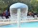 A close-up shot of a mushroom-shaped water fountain in the community pool area, with lounge chairs visible in the background at 5364 Diplomat Ct # 106, Kissimmee, FL 34746