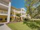 Bright yellow condo building with white trim, balconies, and beautifully landscaped grounds on a sunny day at 709 Lucaya Loop # 1203, Davenport, FL 33897