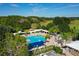 Aerial view of the community pool with sunshades, lounge chairs, and an adjacent golf course at 7125 Harmony Square Dr # 2, Harmony, FL 34773