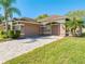 Exterior view of a home showcasing a two-car garage and a paved driveway, surrounded by well-manicured lawn and landscaping at 1004 Costa Mesa Ln, Kissimmee, FL 34744