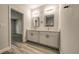 Bathroom with double sinks, framed mirrors, white cabinets, and wood-look tile flooring at 1013 Cannes Dr, Kissimmee, FL 34759