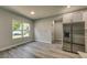 An open dining area with gray wood floors, a window, and stainless steel refrigerator nearby at 1013 Cannes Dr, Kissimmee, FL 34759