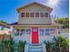 Charming two-story home featuring a red front door and mature landscaping at 103 W Maple St, Davenport, FL 33837