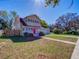 Charming two-story home with a well-manicured front yard, mature trees, and a red front door at 103 W Maple St, Davenport, FL 33837