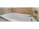 A close up of a white soaking tub with brushed gold fixtures and stone-look tile surround at 1251 Aquila Loop, Celebration, FL 34747