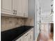 Close-up of a kitchen counter, showcasing white cabinets and black countertops, complemented by stylish tile backsplash at 1251 Aquila Loop, Celebration, FL 34747