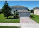 Two-story home featuring a well-manicured front lawn, paver driveway, and neutral-toned exterior with stone accents at 1336 Lattimore Dr, Clermont, FL 34711