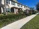 Street view of townhomes with blue shutters, well-maintained landscaping, and a sidewalk at 16180 Arbor Crest Aly, Winter Garden, FL 34787