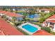 Aerial view of the community pool, surrounded by buildings and trees, with a pond reflecting the sky at 1631 Little Falls Cir # 92, Orlando, FL 32807