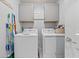 Functional laundry room with a washer, dryer, overhead cabinets, and cleaning supplies at 1982 Birnham Wood Bnd, Kissimmee, FL 34746