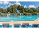 Spacious community pool area with blue lounge chairs and umbrellas for shade at 2313 Duncan Trl, Clermont, FL 34714