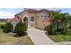 Elegant two-story home with well-manicured lawn, brick driveway, arched window, and a red tile roof at 2375 Pinehurst Ct, Davenport, FL 33837