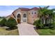 Elegant two-story home with well-manicured lawn, brick driveway, arched window, and a red tile roof at 2375 Pinehurst Ct, Davenport, FL 33837