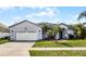 A single-story home has a well-manicured lawn with palm trees and a 2 car garage on a sunny day with blue skies at 2539 Jasmine Trace Dr, Kissimmee, FL 34758