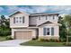 Two-story home featuring stone accents, siding, shutters, a two-car garage, and a well-manicured lawn at 276 Hilltop Bloom Loop, Haines City, FL 33844