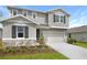 Beautiful two-story home featuring gray siding, dark shutters, and a two-car garage with manicured landscaping at 276 Hilltop Bloom Loop, Haines City, FL 33844