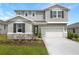 Attractive two-story home showcasing gray siding, dark shutters, a two-car garage, and well-maintained front yard at 276 Hilltop Bloom Loop, Haines City, FL 33844