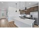 Modern kitchen features a large island with quartz countertop, stainless steel appliances, and stylish pendant lighting at 276 Hilltop Bloom Loop, Haines City, FL 33844