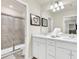 This bathroom features dual sinks with white cabinets, a large mirror, and a tiled walk-in shower at 3624 Lily Ln, Davenport, FL 33897