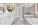 This bathroom has a double vanity with a soaking tub and shower combo. Accented with modern artwork and tile at 3624 Lily Ln, Davenport, FL 33897
