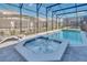 Screened-in swimming pool and bubbling hot tub with surrounding brick pavers in the backyard at 3624 Lily Ln, Davenport, FL 33897