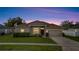 Charming single-story home with a well-manicured lawn and two-car garage at sunset at 3840 Wood Thrush Dr, Kissimmee, FL 34744