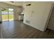Open living room with gray wood flooring and sliding glass doors to the backyard and modern kitchen at 4861 Haines Circle, Orlando, FL 32822