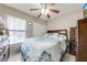Bright bedroom with ceiling fan, large window, and comfortable bed with patterned bedding at 86 Pine Island Cir, Kissimmee, FL 34743