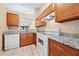 Bright kitchen featuring granite countertops, white appliances, a view to the living room, and wood cabinets at 86 Pine Island Cir, Kissimmee, FL 34743