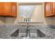 Close-up of a stainless steel sink with granite countertops, white appliances, and a view to the living room at 86 Pine Island Cir, Kissimmee, FL 34743