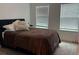 Neutral bedroom offers natural light through two windows and comfortable carpet and a plush bed at 9690 Emerald Berry Dr, Winter Garden, FL 34787
