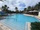 Stunning community pool with a zero entry, sun shelf, and resort style amenities surrounded by lush landscaping and palm trees at 9690 Emerald Berry Dr, Winter Garden, FL 34787