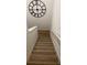 A stairway leads up under a roman numeral clock, featuring elegant white rails and light hardwood steps at 9690 Emerald Berry Dr, Winter Garden, FL 34787
